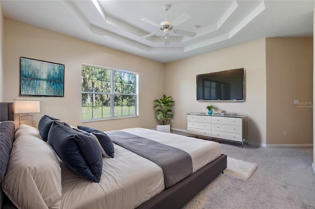 carpeted bedroom with a raised ceiling and ceiling fan