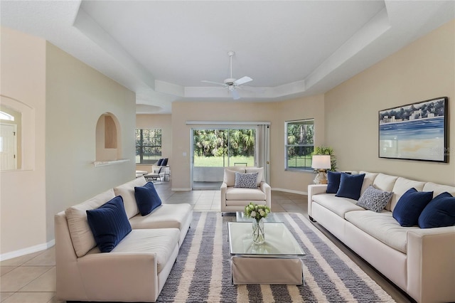 living room with ceiling fan, light tile patterned floors, and a tray ceiling