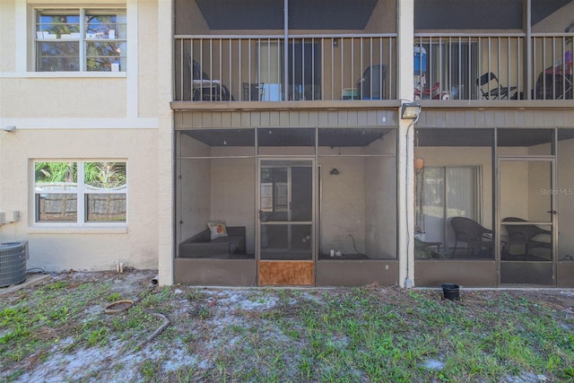 rear view of property featuring a balcony, a sunroom, and stucco siding