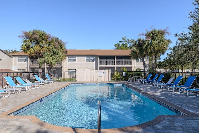 pool with a patio area and fence