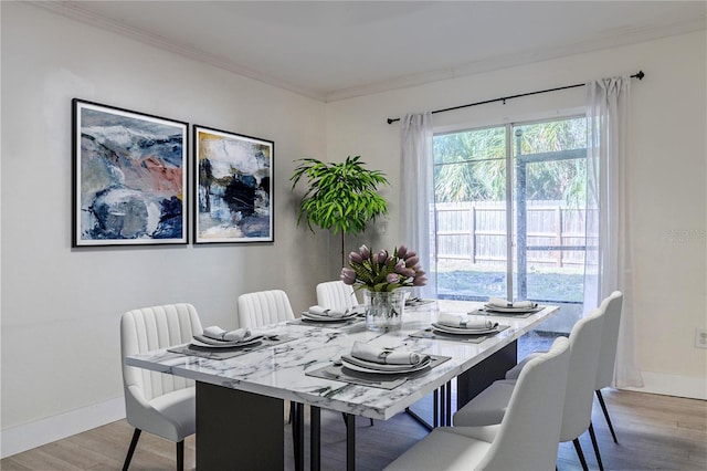 dining space featuring crown molding, light wood-style flooring, and baseboards