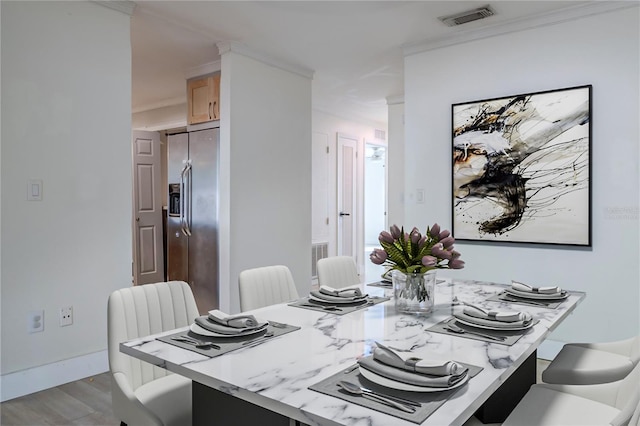 dining room with crown molding, wood finished floors, visible vents, and baseboards