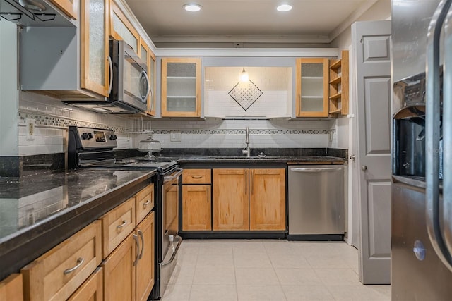 kitchen featuring dark stone countertops, tasteful backsplash, appliances with stainless steel finishes, and a sink