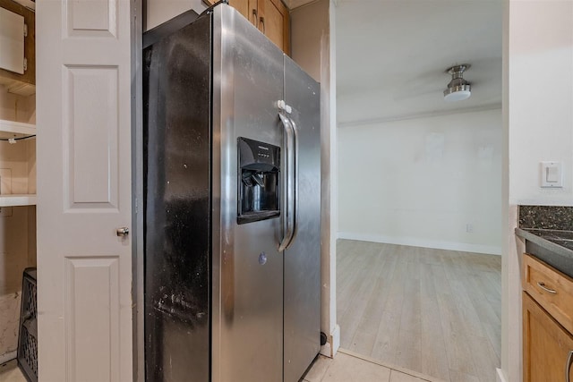 kitchen with dark countertops, baseboards, stainless steel fridge, and light wood-type flooring