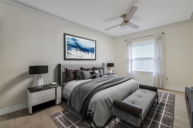 bedroom featuring light wood-type flooring, ornamental molding, and a ceiling fan