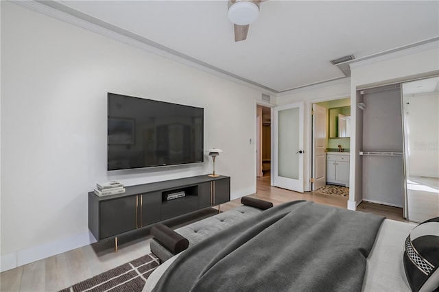 bedroom featuring a sink, wood finished floors, visible vents, and ornamental molding