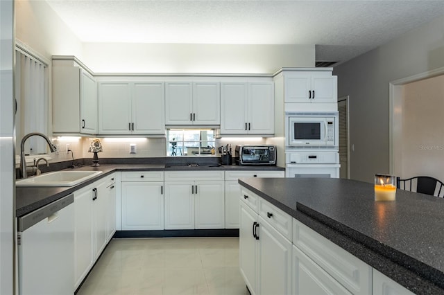 kitchen featuring white appliances, sink, light tile patterned floors, a textured ceiling, and white cabinetry