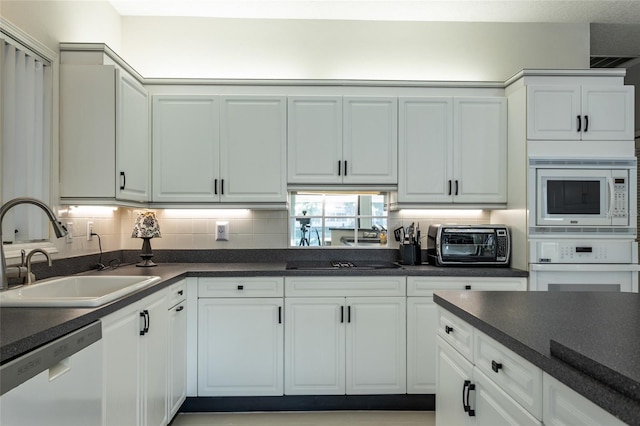 kitchen with white cabinetry, white appliances, sink, and tasteful backsplash