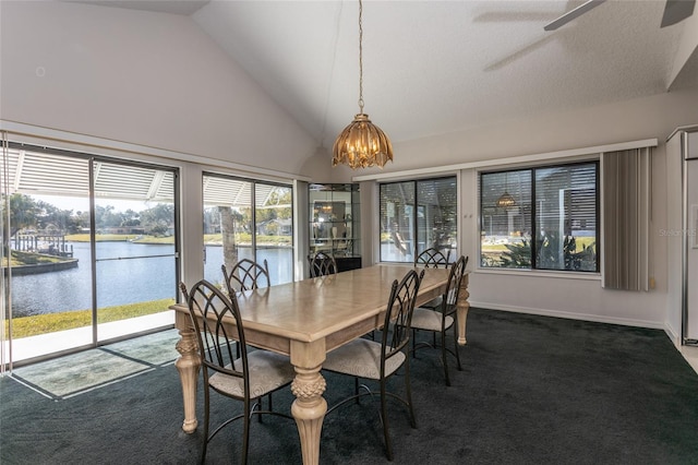 carpeted dining room featuring ceiling fan with notable chandelier, a water view, and high vaulted ceiling