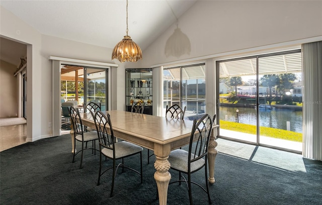 carpeted dining area with high vaulted ceiling, a water view, and an inviting chandelier