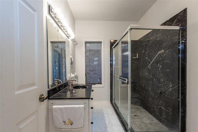 bathroom with a textured ceiling, vanity, and a shower with shower door