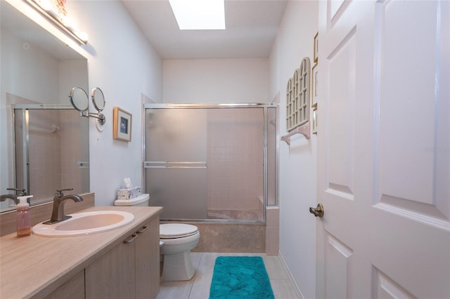 full bathroom with vanity, shower / bath combination with glass door, tile patterned floors, a skylight, and toilet