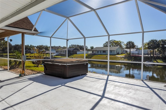 view of patio / terrace featuring a lanai, a water view, and a hot tub