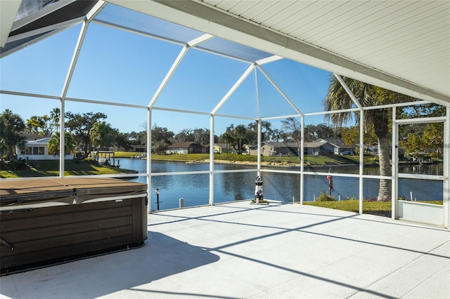 view of patio featuring a lanai, a water view, and a hot tub