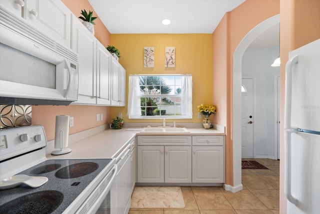 kitchen featuring white appliances, sink, light tile patterned floors, decorative light fixtures, and white cabinets