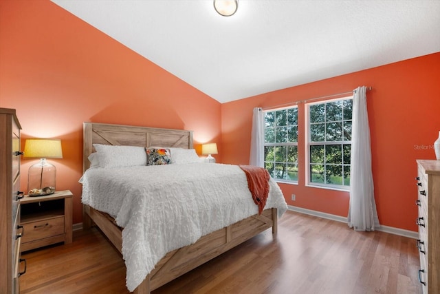 bedroom with lofted ceiling and light wood-type flooring