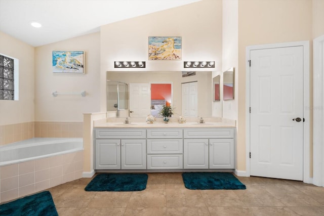 bathroom featuring tiled bath, tile patterned flooring, vanity, and vaulted ceiling