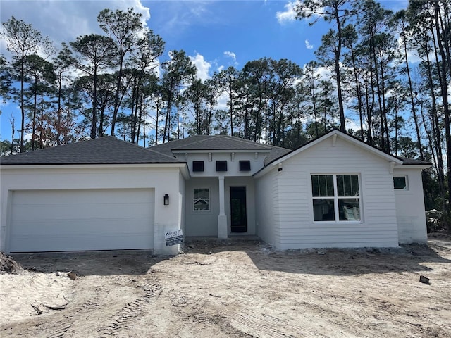 view of front of home with a garage, driveway, and roof with shingles