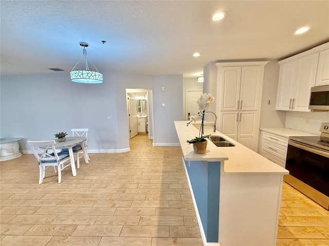 kitchen featuring sink, light hardwood / wood-style flooring, decorative light fixtures, white cabinets, and appliances with stainless steel finishes