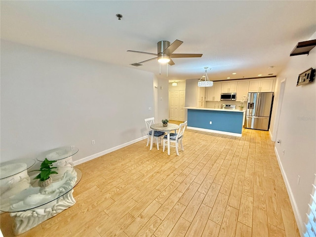 kitchen featuring white cabinets, stainless steel appliances, light hardwood / wood-style flooring, and hanging light fixtures