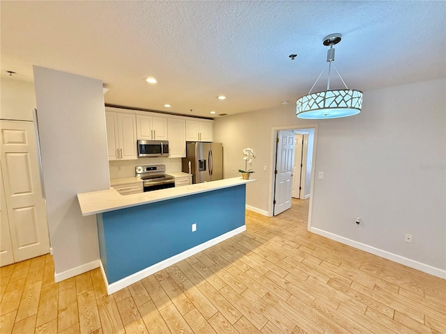 kitchen with light hardwood / wood-style flooring, decorative light fixtures, white cabinetry, kitchen peninsula, and stainless steel appliances