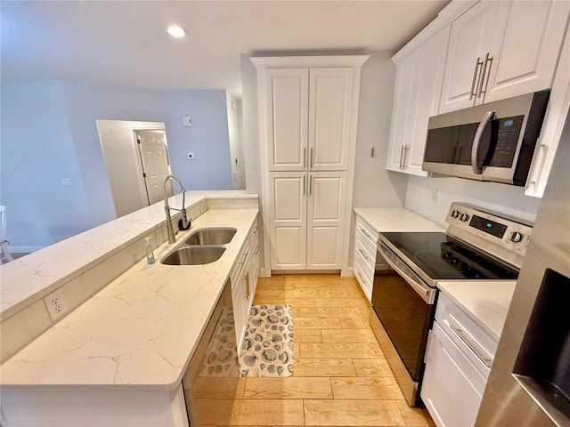 kitchen with white cabinets, sink, light stone countertops, light wood-type flooring, and appliances with stainless steel finishes