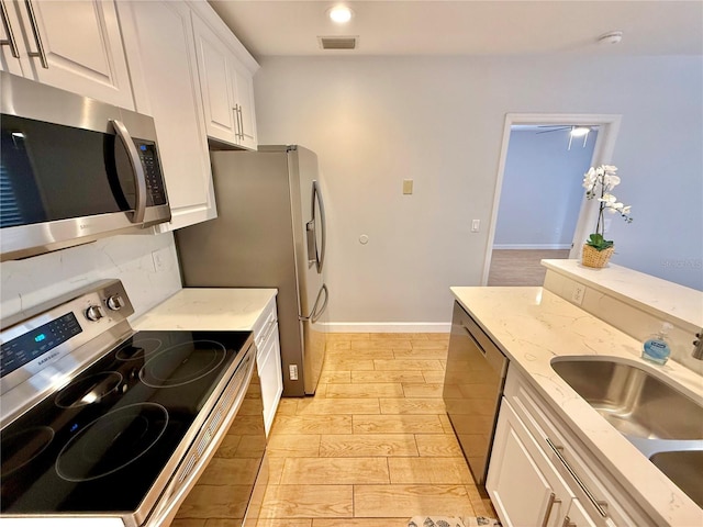 kitchen with decorative backsplash, light wood-type flooring, stainless steel appliances, sink, and white cabinets