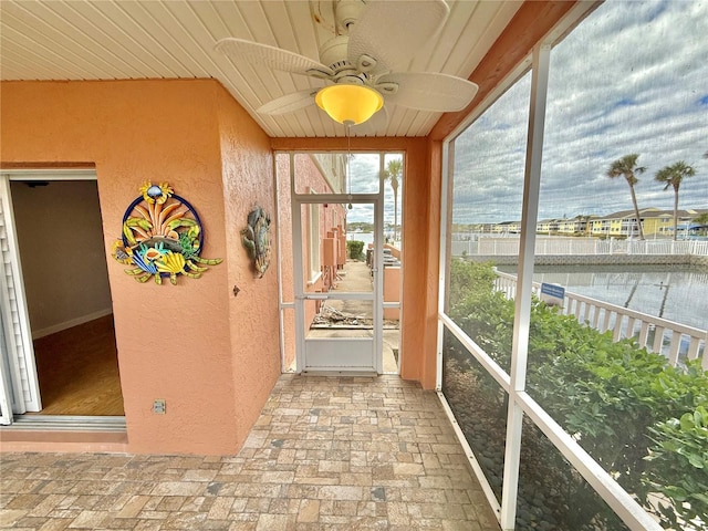 unfurnished sunroom with ceiling fan