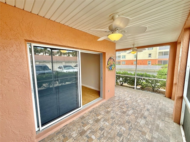 unfurnished sunroom featuring ceiling fan