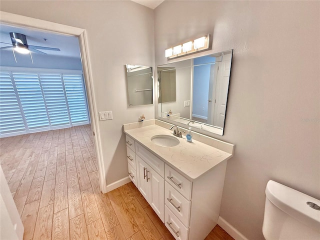 bathroom with ceiling fan, toilet, wood-type flooring, and vanity