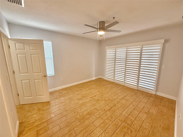 spare room with ceiling fan, light wood-type flooring, and a textured ceiling