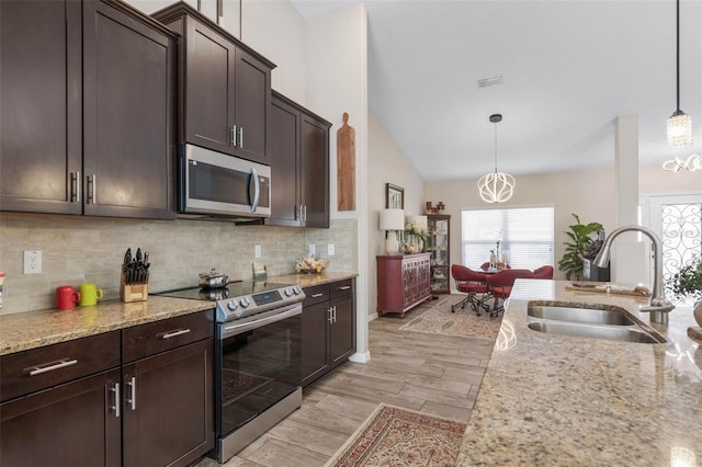 kitchen featuring stainless steel appliances, vaulted ceiling, sink, pendant lighting, and light hardwood / wood-style floors