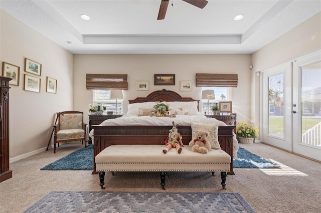 bedroom featuring access to exterior, ceiling fan, french doors, a tray ceiling, and light carpet