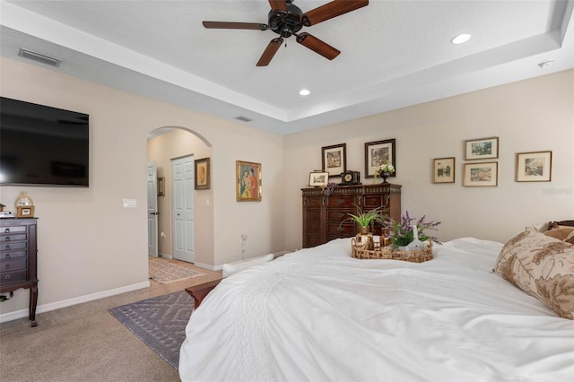 carpeted bedroom with ceiling fan, a raised ceiling, and a textured ceiling