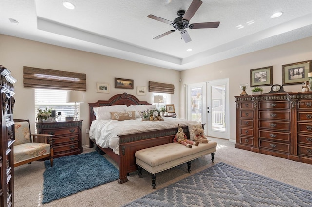 carpeted bedroom with a tray ceiling, access to exterior, ceiling fan, and a textured ceiling