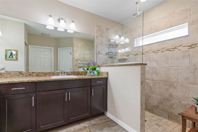 bathroom featuring a tile shower, vanity, and wood-type flooring