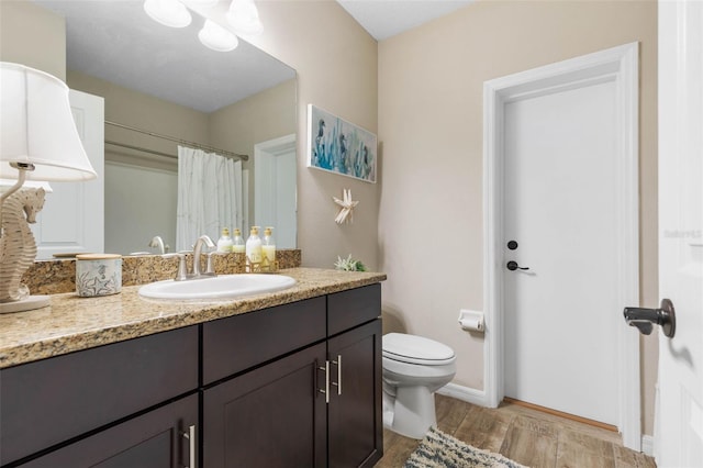 bathroom with curtained shower, vanity, wood-type flooring, and toilet