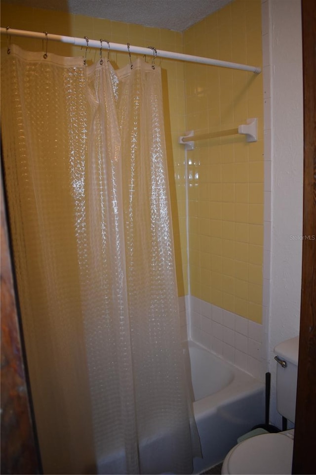 bathroom featuring shower / tub combo with curtain and toilet