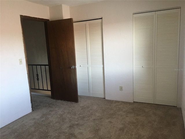 unfurnished bedroom with dark carpet and multiple closets