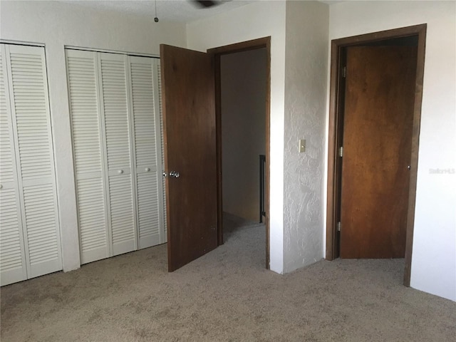 unfurnished bedroom featuring light colored carpet and two closets