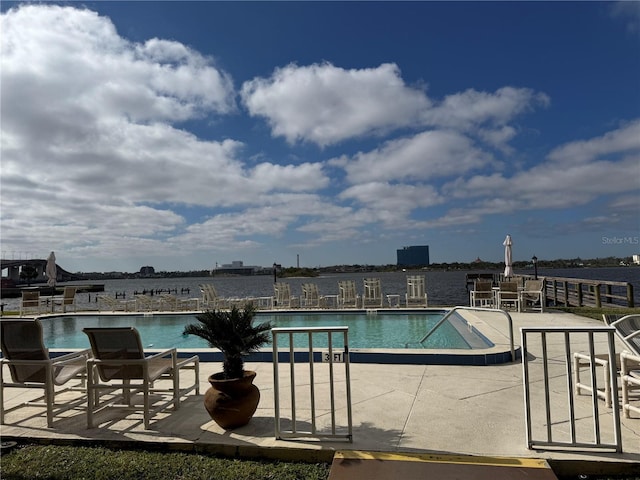 view of swimming pool featuring a water view and a patio