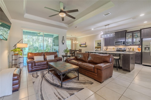 tiled living room featuring a raised ceiling, ceiling fan with notable chandelier, and ornamental molding