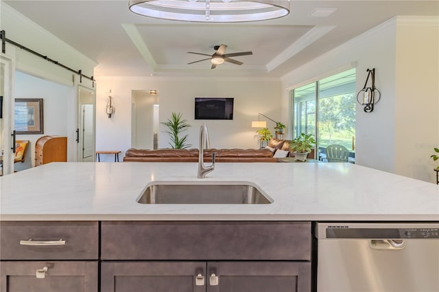 kitchen featuring a barn door, a tray ceiling, stainless steel dishwasher, and sink