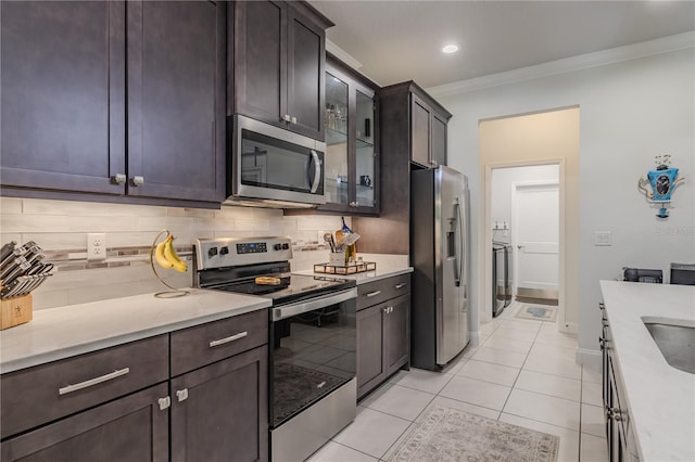 kitchen with backsplash, stainless steel appliances, crown molding, light tile patterned floors, and separate washer and dryer