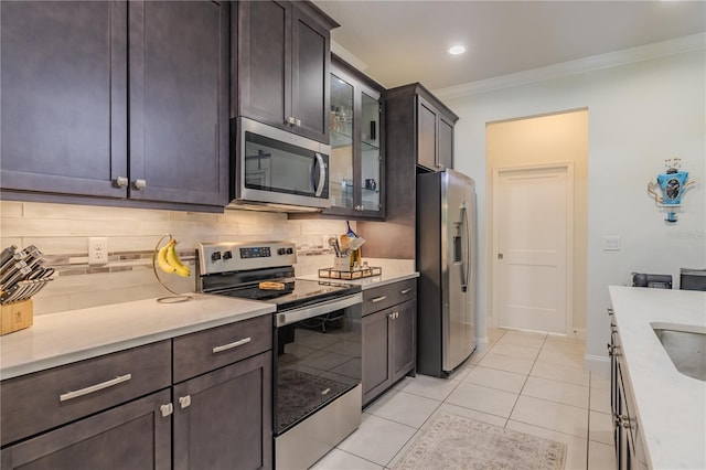 kitchen with backsplash, crown molding, light tile patterned floors, appliances with stainless steel finishes, and dark brown cabinets