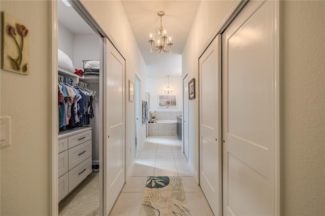 corridor with light tile patterned flooring and a chandelier