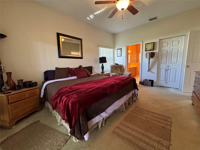 bedroom featuring light carpet, ensuite bathroom, and ceiling fan