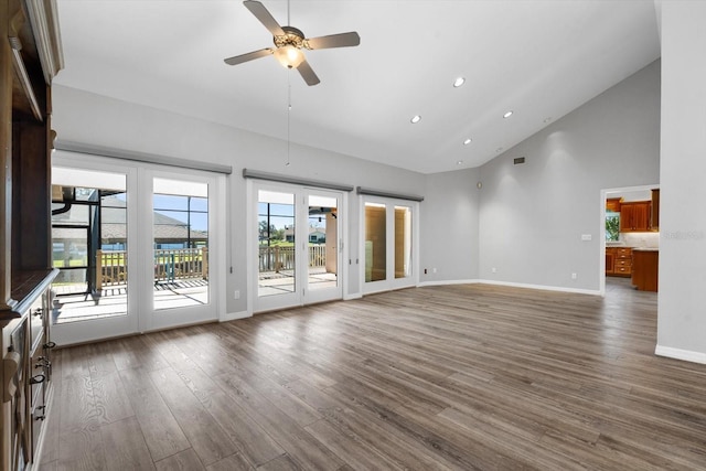 unfurnished living room with dark hardwood / wood-style floors, high vaulted ceiling, ceiling fan, and a healthy amount of sunlight