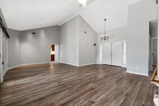 unfurnished living room with ceiling fan with notable chandelier, dark wood-type flooring, high vaulted ceiling, and french doors