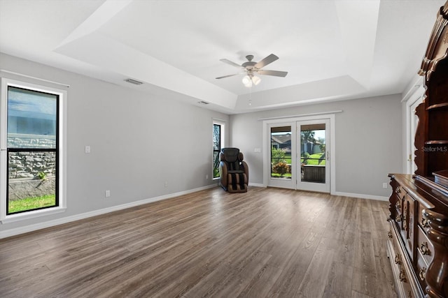 unfurnished living room with a raised ceiling, ceiling fan, and hardwood / wood-style flooring